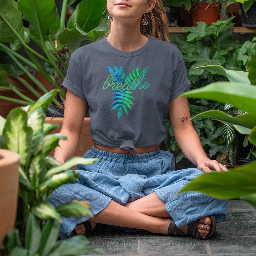 Woman in a green house wearing a breathe grey t-shirt for mindfulness and presence.