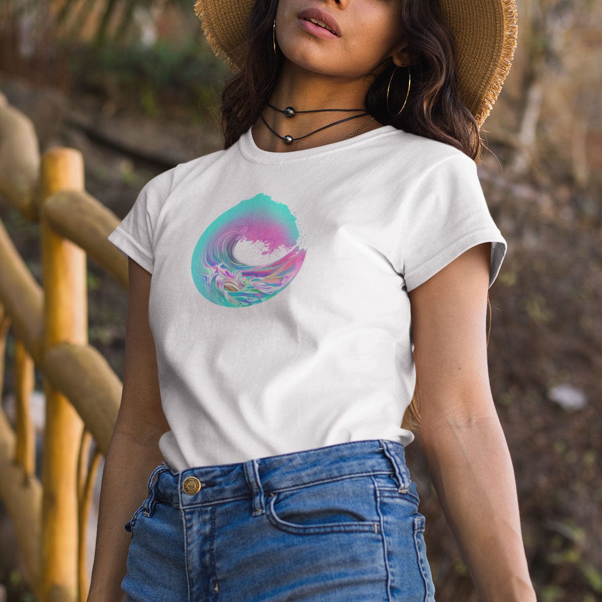 Woman at beach wearing circular wave pink teal vibrant white t-shirt for ocean flow and surrender.