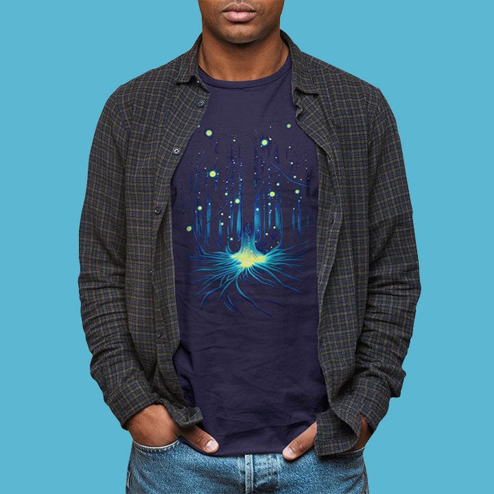 Man wearing fireflies glowing in wooded forest grove navy t-shirt for night magic and awe of nature.