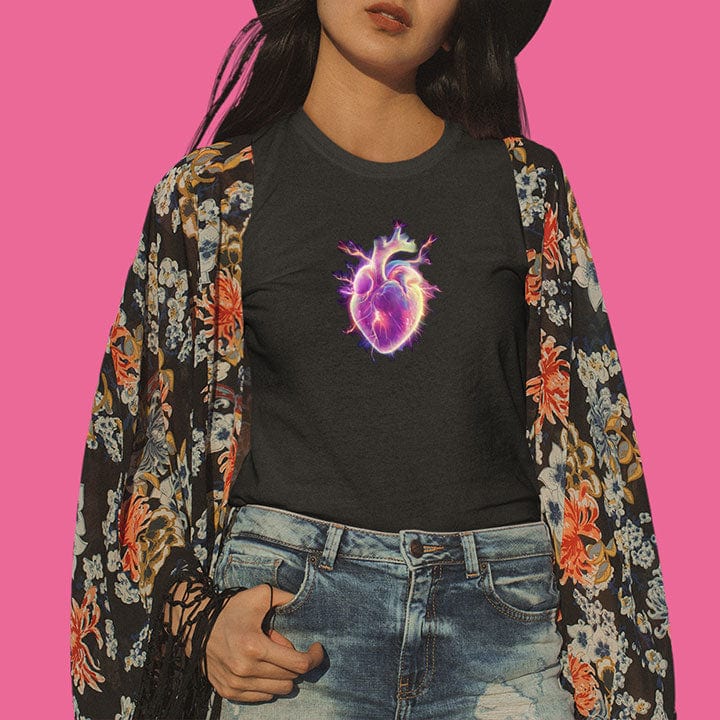 Woman wearing glowing pink and purple electric heart black t-shirt for vulnerability and aliveness.