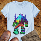 Bigfoot silhouette filled with aurora borealis and forest landscape on light blue t-shirt for cryptid mystery wilderness.