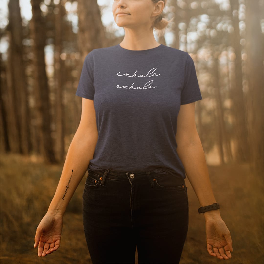 Woman in the forest wearing inhale exhale dark grey t-shirt for breath work and mindfulness.