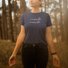 Woman in the forest wearing inhale exhale dark grey t-shirt for breath work and mindfulness.