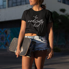 Woman holding a skateboard wearing a be radically kind black t-shirt for compassion and gentle rebellion.